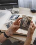 Senior woman is looking her own old photos at home. Elderly woman has got smile while remembering how young and beatiful she was. Selective focus. Photo was taken in 1953
