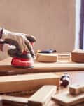 woman using sander to work with wood furniture