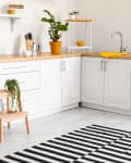 Interior of modern kitchen with white counters and wooden step stool