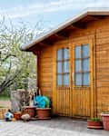 Small beautiful wooden house shed or storage hut for garden tools equipment and bicycles at backyard at beautiful american or european countryside backyard. Cozy rural yard stuff warehouse.