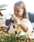 little girl decorating Christmas tree with DIY paper chain