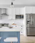 Modern White Kitchen with Stainless Steel Luxury Appliances. Contemporary dual tone cabinets with white subway tile backsplash.