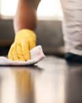 Man hands, cleaning gloves and wipe on a table with a wash cloth and housekeeping. Home, countertop and male person with disinfectant and scrub with washing in a apartment with maid and housekeeper