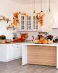 Autumn kitchen interior. Red and yellow leaves and flowers in the vase and pumpkin on light background