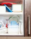 kitchen cabinet full of plastic food containers arranged in a haphazard manner
