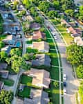 Parallel residential streets with back alleys and row of single-family houses surrounding by lush green trees in suburbs Dallas Fort Worth metro complex, suburban homes swimming pool, aerial. USA