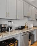 A Modern grey kitchen cabinets with elegant gold hardware on doors and backs.