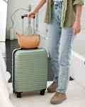 Unrecognizable young woman coming leaving with luggage to hotel room.