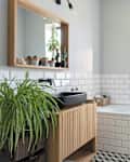 Modern bathroom in industrial design in stylish interior. White tiles, wooden cabinet and mirror and bathroom sink in black colour in new apartment.