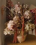 Dry hydrangea, poppy and amaranth in stylish vase close up. Fall decor in modern living room. Thanksgiving and Halloween. Autumn floral arrangement