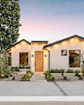 Modern single-story house with a minimalist garden at sunset, featuring clean lines and warm lighting.