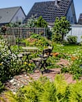 wild garden - herb spiral in the garden with fresh herbs and flowers and old chairs and table