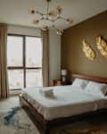 Traditional bedroom with wooden bed frame, chandelier and golden wall decor