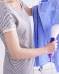 Women steaming shirt in room