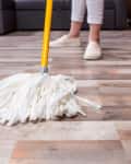 Close-up partial view of woman cleaning floor with string mop