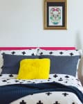 Colorful blankets on ladder in room with blue and yellow pillow.