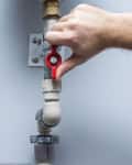 Man working at pipes. Turning on or turning off water supply in the boiler room. Plumbing concept.
