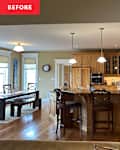 Spacious kitchen with wooden cabinets, granite island, bar stools, and a dining table, featuring flowers and kitchen appliances.