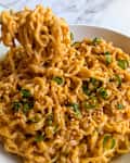 Someone taking forkful of peanut butter ramen.