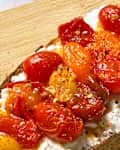 Toasted bread topped with creamy ricotta cheese and roasted cherry tomatoes, drizzled with olive oil and spices.
