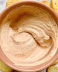 Creamy dip being scooped with a toasted bread slice.