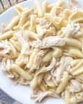Cavatappi pasta mixed with shredded chicken on a platter.