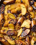 Sautéed sausages with sliced apples and onions in a cast iron skillet, garnished with fresh thyme.