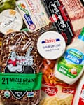 Assorted grocery items including bread, yogurt, sauces, bacon, and fresh produce.