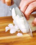 close up of hands dicing a white onion