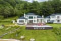 Large white house with blue roof, surrounded by trees, features a pool and deck with colorful bean bags, labeled "In the Soop."