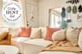 Sunny white living room with comfy sofa and throw pillows and blankets with Best list home essentials 2024 seal in upper left