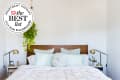 Image of bed with lots of pillows, white shiplap wall, hanging plant. Seal in upper left corner reads "Apartment Therapy The Best List 2024 Silk Pillowcases"