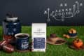 Grounds & Hounds Puppy Bowl Blend coffee with footballs, mug, and snacks on artificial grass, chalkboard play diagram in background.
