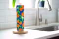 Colorful paper towel roll with orange fruit design on a kitchen counter near a sink.