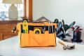 bright yellow-orange tool bag with tools inside. Sitting on counter in home setting