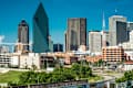 Dallas skyline with modern skyscrapers, including a triangular glass building, under a clear blue sky.