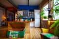 Open kitchen with blue wall, wooden island, hanging plants, and a yellow armchair near large windows.