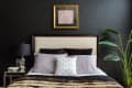 A bed with brown bedspread and a black wall