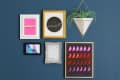 Gallery wall with framed art, including a pink "Feeling good" print, abstract watercolor, and a geometric plant holder.