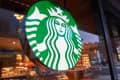 Starbucks logo on a glass window with a view of the store interior and street outside.