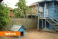 Backyard with a blue doghouse, wooden fence, and a blue house with stairs.