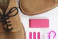 Tan suede shoes with black laces, pink shoe care kit including brush, eraser, and files.