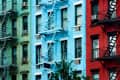 Colorful apartment buildings with fire escapes; green, blue, and red facades.