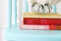 Aqua chair with a vase of white roses on top of stacked books, including "let's start to cook."