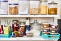 Organized pantry shelves with labeled jars of oats, pasta, polenta, spices, and baking ingredients.