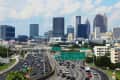 Busy highway leading into a city skyline with tall buildings and traffic signs.