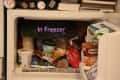 Freezer filled with various ice cream tubs, frozen vegetables, and food packages.