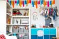 Colorful kids' room with tassel garland, white chair, patterned rug, and blue storage cubes.