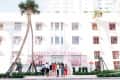 People standing outside the Museum of Ice Cream, a white building with pink accents and palm trees.