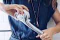 Person in a blue shirt holding a chrome showerhead, adjusting the settings.
